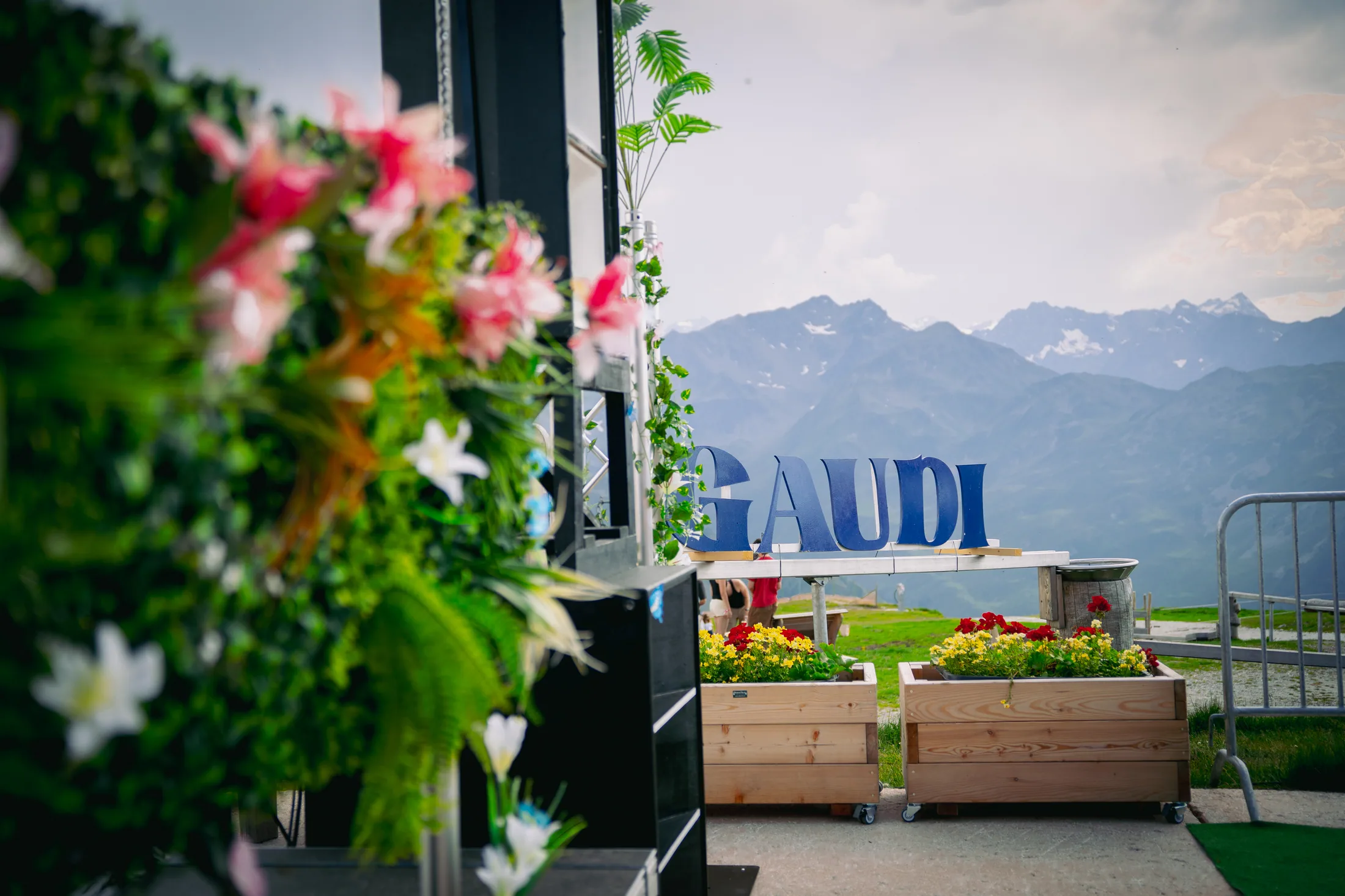 Flowers framing the Gaudi sign and Tyrolean mountain panorama