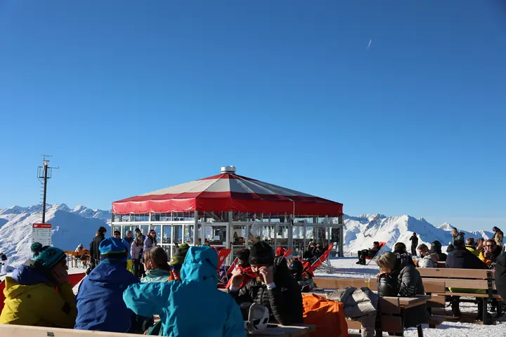 Skiers relaxing at the red Hoadl terrace above the mountains